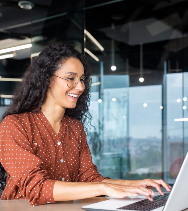 A woman with glasses working on a laptop